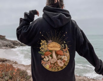 May include: Black hoodie with a graphic of mushrooms, flowers, and moons on the back. The graphic is in a vintage style with gold accents.