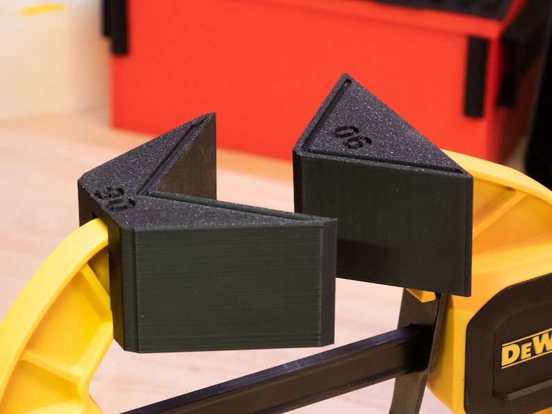 May include: A yellow and black clamp with two black triangular corner clamps. The corner clamps are labeled "06" and "05".