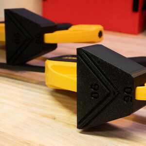 May include: Two black and yellow woodworking clamps with a triangular shape and the number "90" printed on the side.