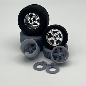 May include: A set of four black and silver model car wheels with tires. The wheels are different sizes and have a variety of spoke designs. There are also two gray plastic brake rotors included.