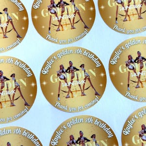 Puede incluir: Una colecci&oacute;n de pegatinas circulares doradas. Cada pegatina presenta el texto "Kaylee's golden 8th birthday" en una fuente curva. Un gr&aacute;fico de bailarinas est&aacute; en el centro, con la palabra "GOLDEN" y "HUNTRIX" debajo. La frase "Thank you for coming!" tambi&eacute;n est&aacute; incluida.