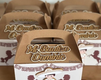 May include: Brown favor boxes with handles, featuring a white and brown design. The boxes are decorated with a cartoon mariachi figure, horses, and the text "Mi Bautizo Dominic". The boxes are suitable for a baptism.