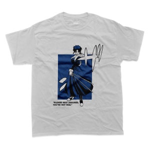Pode incluir: Uma camiseta branca com uma ilustração azul e preta de um personagem da série de anime "D.Gray-man". O personagem está segurando duas espadas e o texto "PLEASE REST ASSURED, YOU'RE NOT ROA." está impresso abaixo da ilustração.