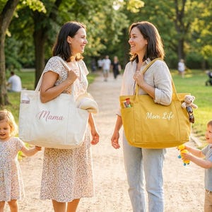 May include: Two women and two children are walking in a park. One woman carries a cream-colored tote bag with "Mama" printed on it. The other woman carries a yellow tote bag with "Mom Life" printed on it. The children are holding hands.