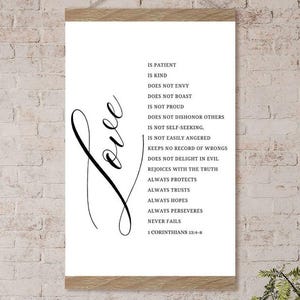 Op de afbeelding: Een zwart-witte printbare wandkunstprint met het woord "Love" in een cursief lettertype en een lijst met kenmerken van liefde uit 1 Korintiërs 13:4-8.