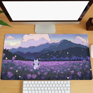 May include: A purple and blue mountain landscape with a white cat in a field of purple flowers. The scene is on a mouse mat with a keyboard and a computer monitor in the background.