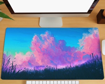 Puede incluir: Una alfombrilla de escritorio colorida con un cielo rosa y morado y nubes sobre una silueta oscura de hierba. La alfombrilla está sobre un escritorio de madera con un monitor de ordenador, un teclado y un ratón.