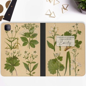 Puede incluir: Una cubierta de cuaderno de cuero marrón con un diseño floral. La cubierta tiene una etiqueta que dice "Composition Notebook College Ruled Emily".