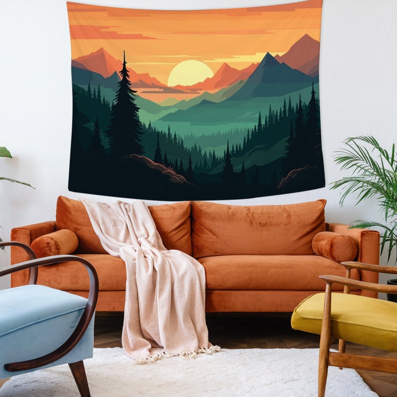 Op de afbeelding: Een wandkleed met een zonsondergang over een bergketen met een bos op de voorgrond. De kleuren zijn oranje, geel, groen en blauw.
