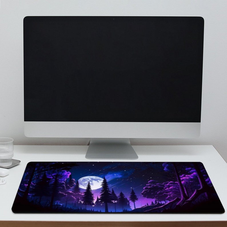 May include: A purple and blue mouse mat featuring a forest scene with a full moon in the background. The moon is white with a blue glow. The forest is dark with tall trees and a starry sky.
