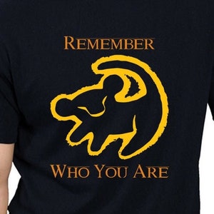 Könnte beinhalten: Schwarzes T-Shirt mit einer gelben Löwen-Silhouette und dem Text "Remember Who You Are".