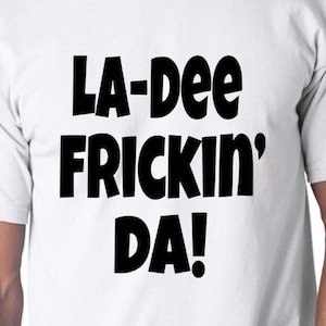 May include: White t-shirt with black text that reads "LA-dee frickin' DA!"