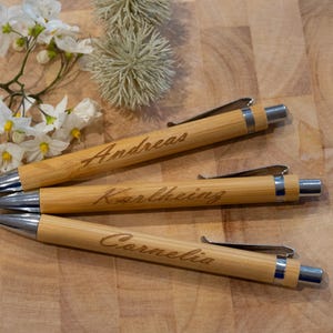 Puede incluir: Tres bol&iacute;grafos de madera con detalles plateados y nombres personalizados: Andreas, Karlheinz y Cornelia.