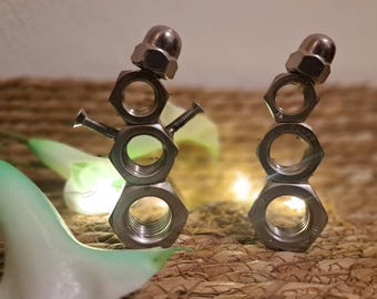 Puede incluir: Dos esculturas caprichosas de muñecos de nieve hechas de tuercas y tornillos metálicos. Los muñecos de nieve tienen una tuerca para la cabeza, dos tuercas para el cuerpo y tornillos para los brazos. El fondo es una textura tejida con iluminación suave.