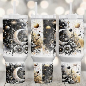 May include: Three stainless steel tumblers with a black and gold design featuring a crescent moon, stars, and floral elements. The tumblers are white with a black and gold design.