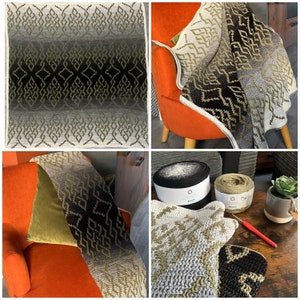 May include: A black, green, and white crocheted throw blanket with a geometric pattern. The blanket is draped over a chair and there are two balls of yarn in the foreground.