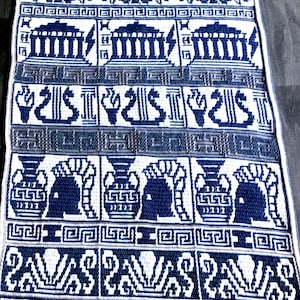 May include: A white crocheted blanket with a blue Greek key pattern. The blanket features a repeating pattern of Greek urns, columns, and the word "PAVA".