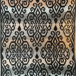 May include: A crocheted throw pillow with a geometric pattern in shades of gray, black, and white.