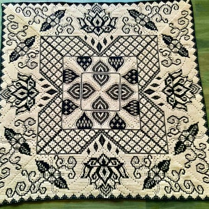 May include: A black and white crocheted throw blanket with a geometric pattern. The blanket features a central square with a repeating design of hearts and diamonds.