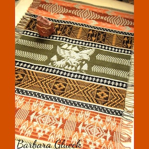 Peut inclure: Une tapisserie tissée avec un motif géométrique dans des tons d'orange, de brun, de vert et de blanc. La tapisserie présente un motif d'oiseau stylisé et le texte "Barbara Glueck".