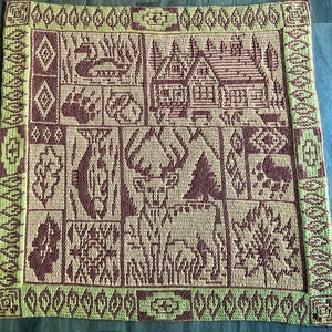 May include: A brown and green crocheted rug with a geometric pattern. The rug features a variety of designs, including houses, trees, and animals.
