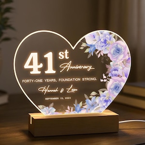 May include: Heart-shaped anniversary light with the text "41st Anniversary" and floral accents. The base is wooden, and the light displays the names "Hannah & Leon" and the date "September 13, 2024".