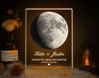 May include: A personalized LED night light with a crescent moon image, the names "Katie & Justin", and the text "The day you asked and I said yes 02.23.2021 | Oxwich Bay".