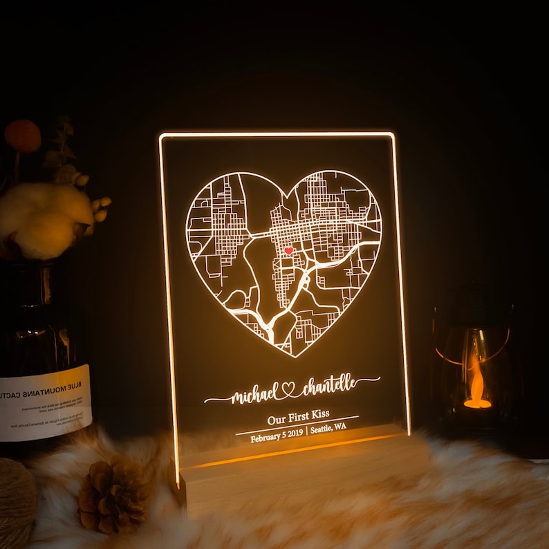 Pu&ograve; includere: Un cartello in acrilico bianco illuminato con una mappa di Seattle, Washington a forma di cuore. Il testo "michael &hearts; chantelle" &egrave; scritto sotto la mappa, insieme a "Our First Kiss, February 5, 2019 | Seattle, WA".