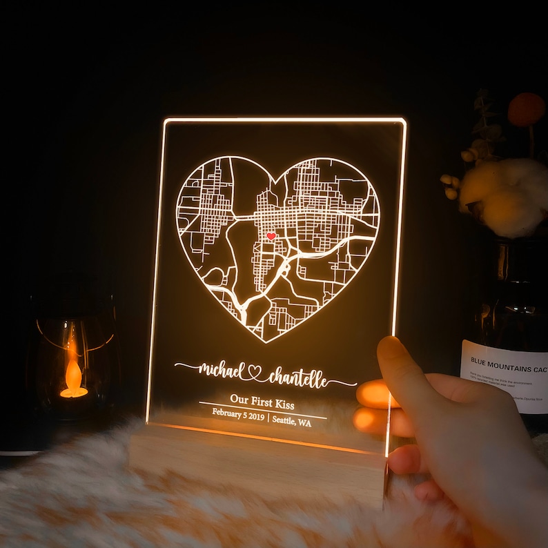 Pu&ograve; includere: Un cartello in acrilico bianco illuminato con una mappa di Seattle, Washington a forma di cuore. Il testo "michael &hearts; chantelle Our First Kiss February 5 2019 | Seattle, WA" &egrave; sotto la mappa.
