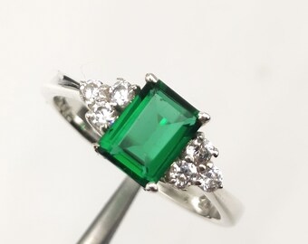 Anillo de compromiso de corte esmeralda con solitario de diamante y piedra preciosa verde.