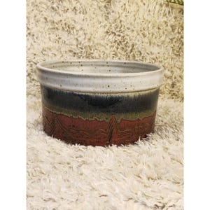 Könnte beinhalten: Ein Set aus drei Keramikbechern mit gesprenkelter, matter Oberfläche. Die Becher sind in Creme-, Hellgrau- und Dunkelgrautönen gehalten. Jeder Becher hat ein schlichtes, minimalistisches Design, perfekt für Kaffee oder Tee.