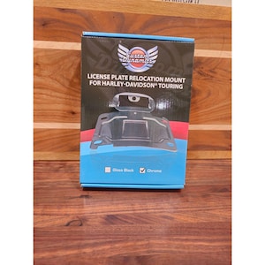 May include: A product box for a license plate relocation mount for Harley-Davidson Touring motorcycles. The box is black, blue, and red with the "Custom Dynamics" logo. The box indicates the product is available in gloss black and chrome.
