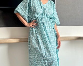 May include: A woman wearing a long, light blue and white patterned kaftan dress with a drawstring waist.