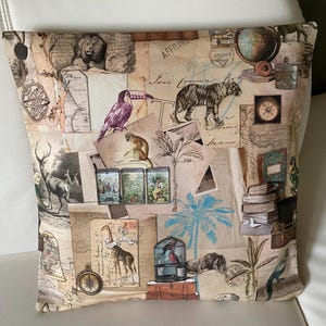 Könnte beinhalten: Dekoratives Kissen mit einem Collage-Design, das Vintage-Karten, Illustrationen von Tieren wie Tiger, Löwe und Giraffe sowie einen Globus zeigt. Die Farbpalette umfasst Beige, Braun und einen Hauch von Blau und Lila.
