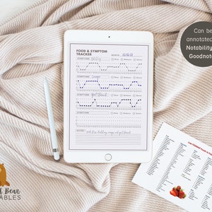 May include: A printable food and symptom tracker on a white tablet with a stylus. The tracker has sections for symptoms, notes, and a calendar. The tablet is on a white blanket. A separate sheet of paper with a list of low FODMAP foods is also visible.
