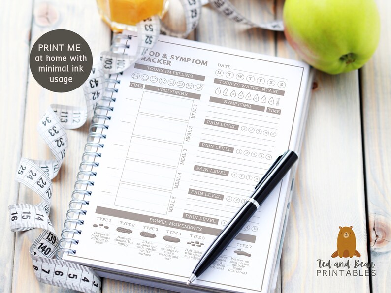 May include: A printable food and symptom tracker journal with a brown cover and a black pen. The journal has sections for tracking food, drink, water intake, pain levels, and bowel movements. The journal is on a wooden surface with a measuring tape and a green apple.