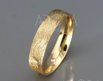 May include: A gold wedding band with a textured, brushed finish. The band has a small diamond set into the side.