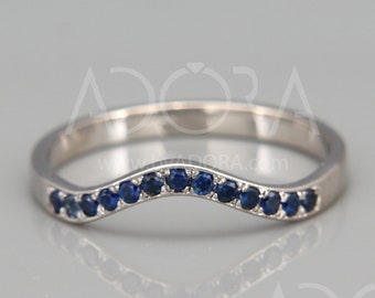 May include: A silver band ring with a curved row of blue sapphires.
