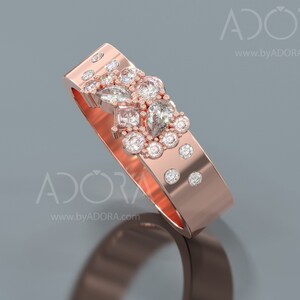 Pu&ograve; includere: Un anello con fascia in oro rosa con un gruppo di piccoli diamanti e un diamante pi&ugrave; grande a forma di pera al centro.