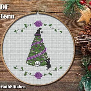 May include: Cross stitch pattern for a spooky Christmas tree with a witch's hat on top, purple ribbon, and a black cat. The pattern is in a white embroidery hoop on a wooden background.