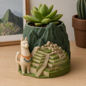 May include: A dark green planter shaped like a mountain landscape featuring a sculpted beige llama with a colorful saddle and a detailed miniature representation of Machu Picchu ruins on the front, containing a green succulent plant.