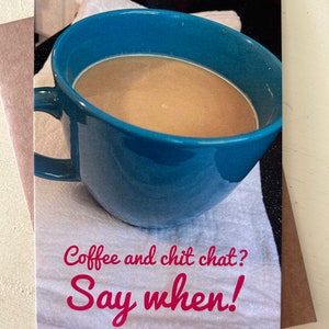 May include: A blue mug filled with coffee on a white towel with the text "Coffee and chit chat? Say when!" in pink.