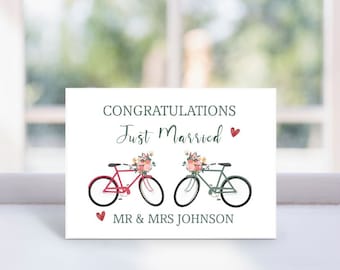 May include: A white greeting card with the words "CONGRATULATIONS Just Married" in green script. Two bicycles, one red and one green, are decorated with flowers. The card also includes the names "MR & MRS JOHNSON" and red hearts.