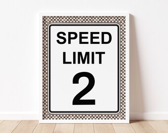 Puede incluir: Una impresión enmarcada en blanco con un borde a cuadros en blanco y negro. La impresión presenta una señal de límite de velocidad blanca con texto negro que dice "SPEED LIMIT 2".