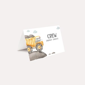 May include: A white card with a yellow dump truck illustration and the text "CREW ENERGY SNACKS".