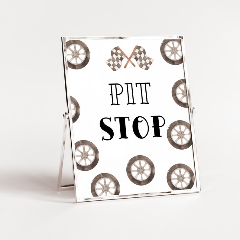 May include: A white sign with black text that reads "PIT STOP" and a checkered flag design. The sign is surrounded by a pattern of brown tire prints.