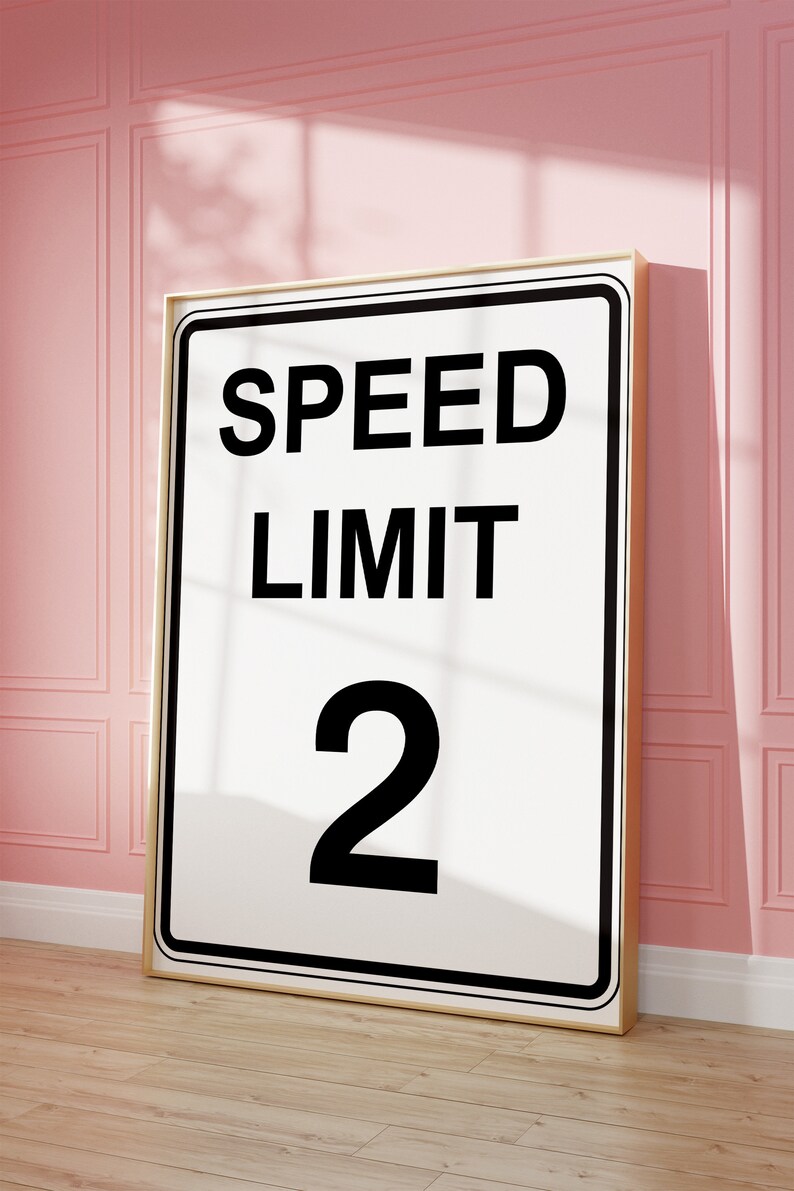 May include: A white sign with black text that reads "SPEED LIMIT 2" in a gold frame.