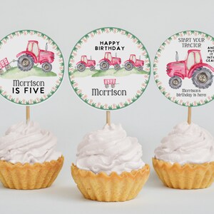 May include: Three round cupcake toppers with a red tractor theme. The toppers feature a red tractor with a green wagon, a line of red tractors, and a single red tractor with the text "Start your tractor and put it into gear!" The toppers are decorated with green and pink floral borders.