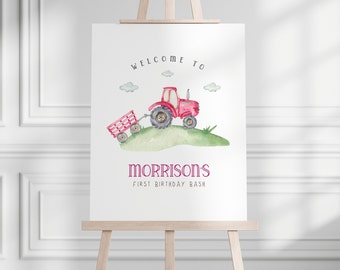 Könnte beinhalten: Willkommen zum Morrison's First Birthday Bash Schild mit einem roten Traktor, der einen Wagen auf einem grünen Grasberg zieht. Das Schild steht auf einem Staffelei.