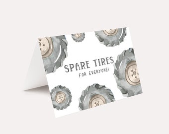 May include: A white card with a grey and white watercolour illustration of tyre treads. The text "Spare Tyres for Everyone!" is printed in black on the card.